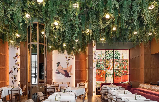 A restaurant dining room under a ceiling of hanging plants, designed by B3 Designers