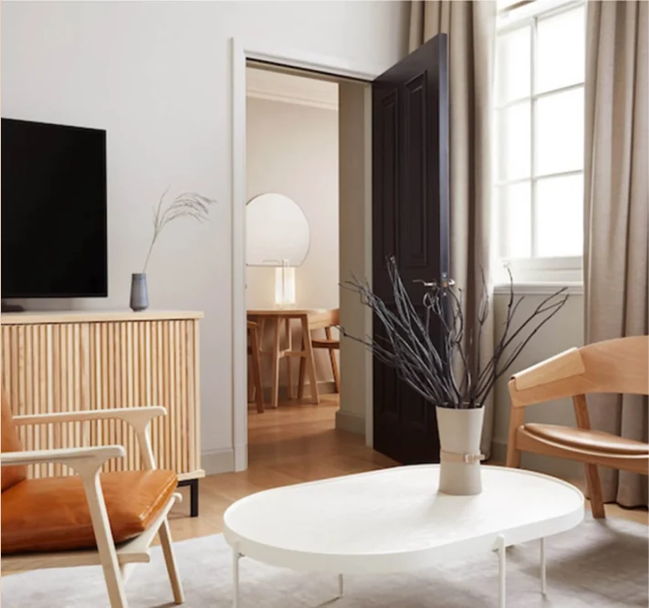 A hotel suite with a cream sofa and timber joinery, designed by B3 Designers