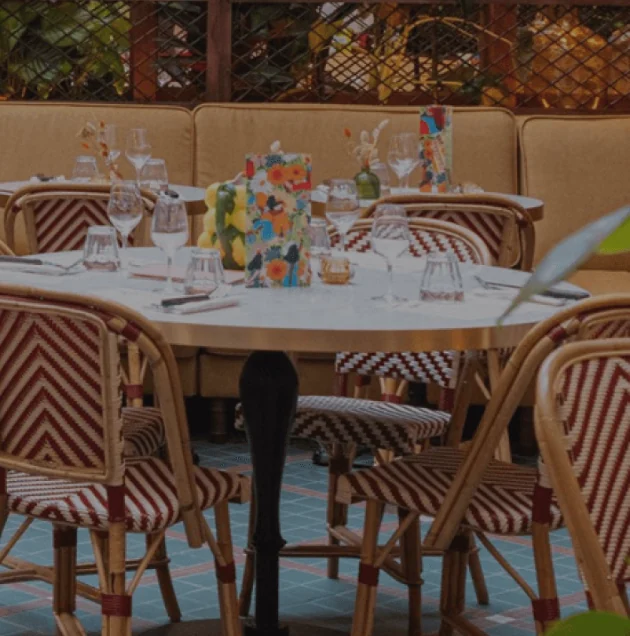 A restaurant terrace with rattan chairs and tiled floor, designed by B3 Designers